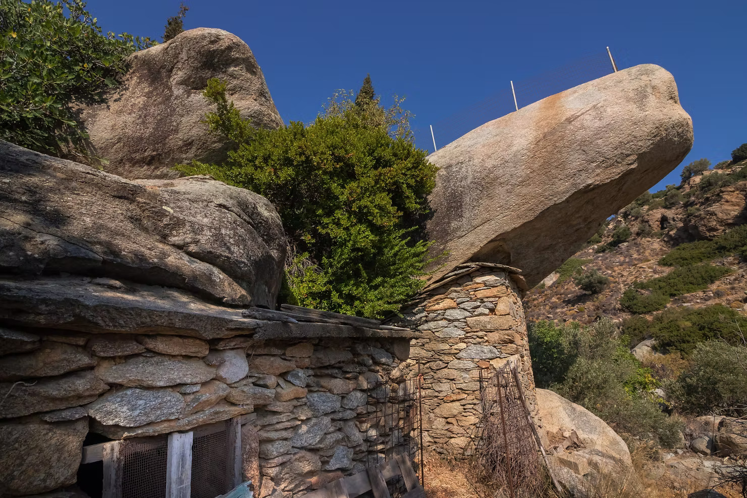 Stone walls and massive boulders forming a natural shelter in Ikaria