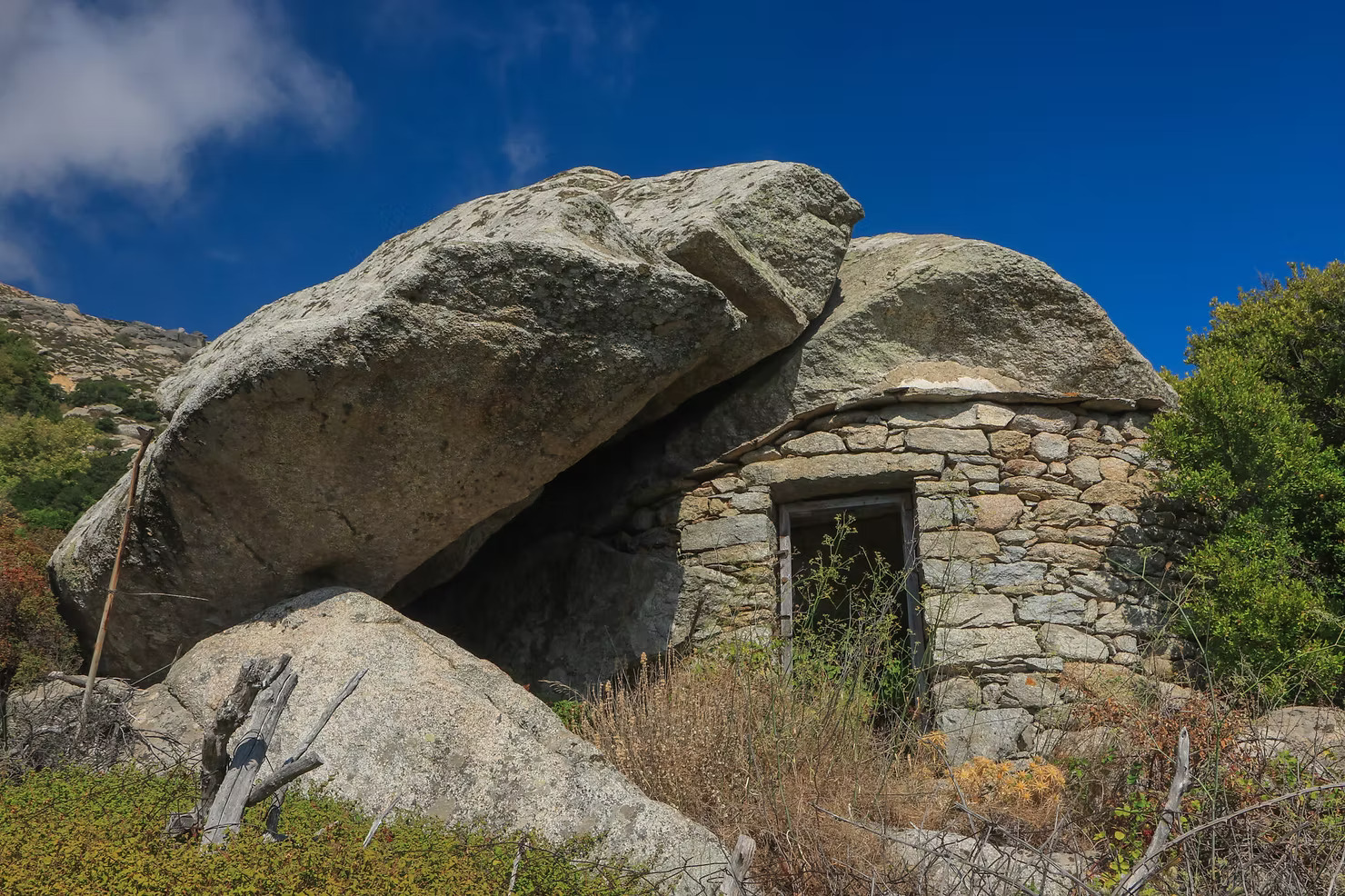 Abandoned pirate house doorway framed by granite boulders in Ikaria