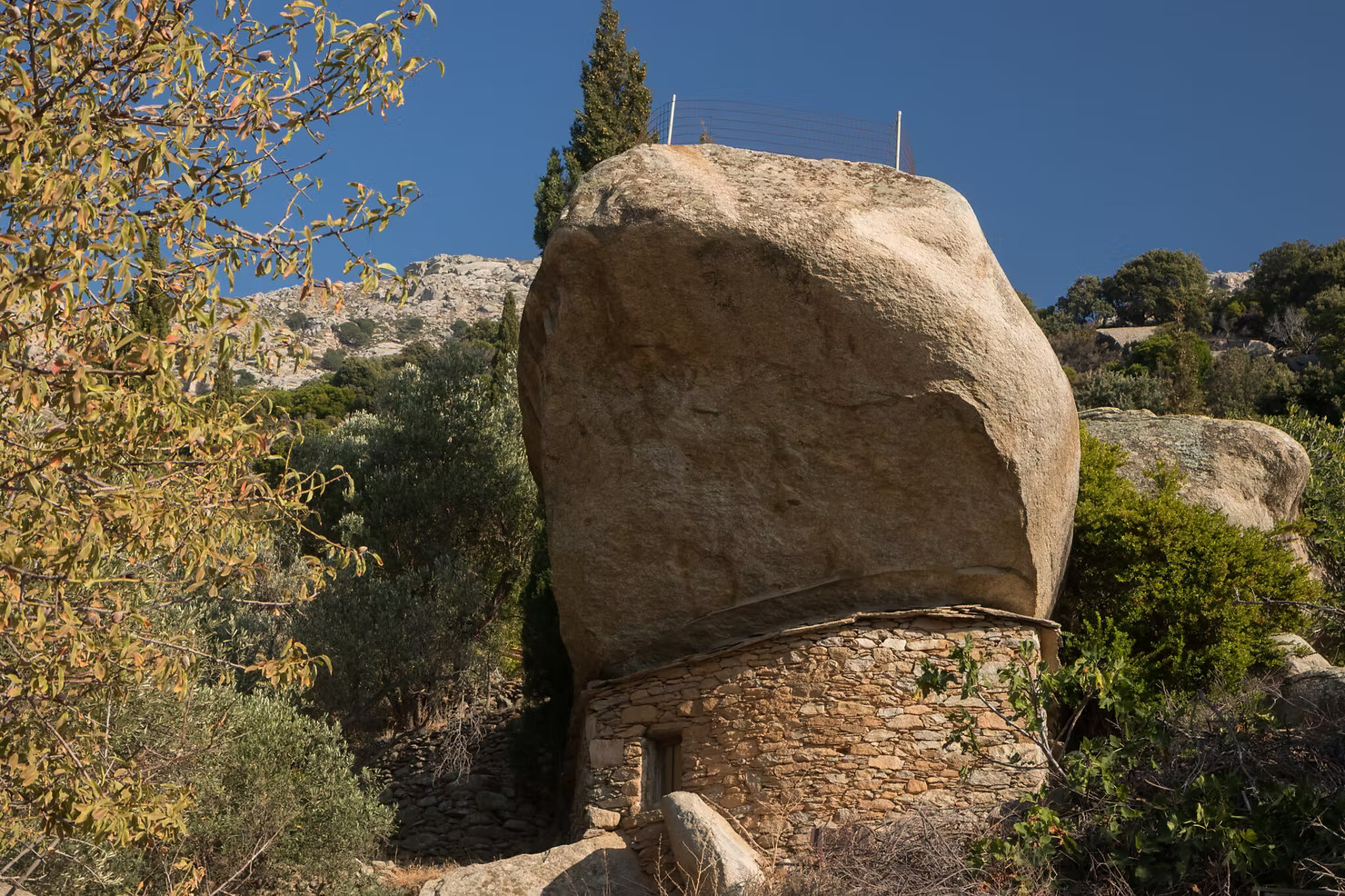 Massive boulder balancing over a stone pirate house in Ikaria's mountains